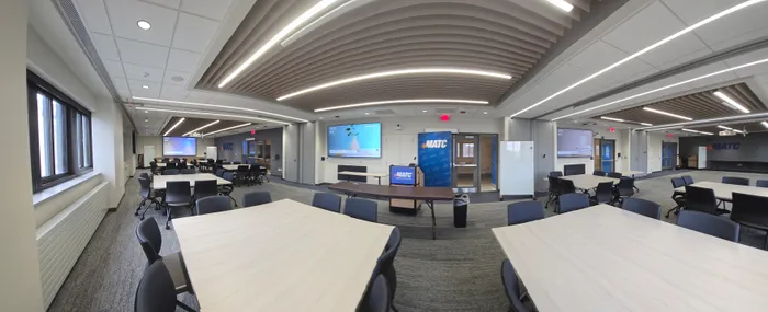 A third panoramic view of the divisible conference room showing both seating sections and the wall-mounted displays on each side. Eight cameras and 24 speakers in one room.