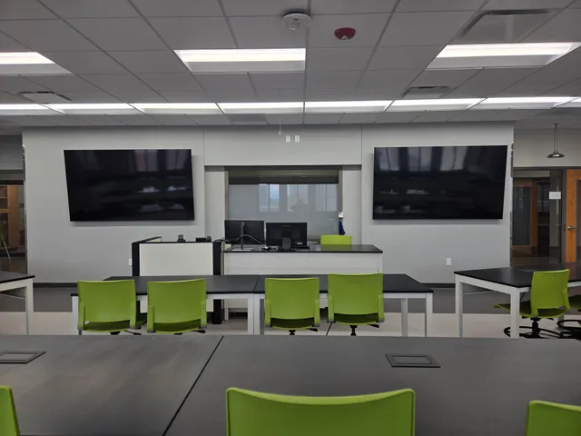 The same science lab viewed from the instructor station, showing two large flat-panel displays flanking a built-in presentation screen.